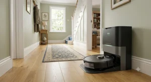 Sleek quiet robot vacuum returning to its self-emptying charging station in a bright hallway
